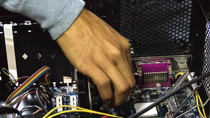 Hand arbeitet im Inneren eines PC-Gehäuses am Mainboard